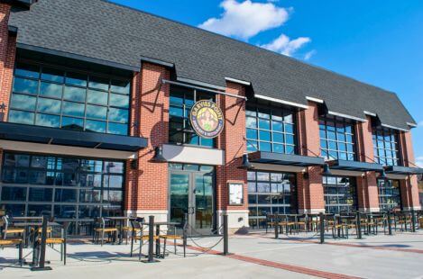 Modern craft brewery storefront with brick exterior, large windows, and outdoor patio seating area