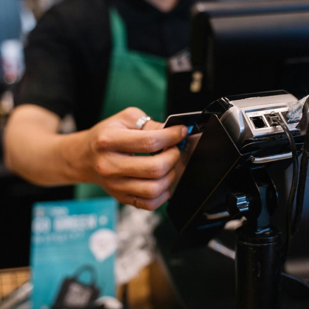 Employee swiping credit card on POS payment terminal at restaurant counter