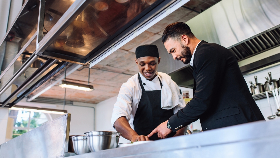 Restaurant owner and chef reviewing operations in the kitchen — understanding state-by-state cost differences is essential for operators making expansion and pricing decisions