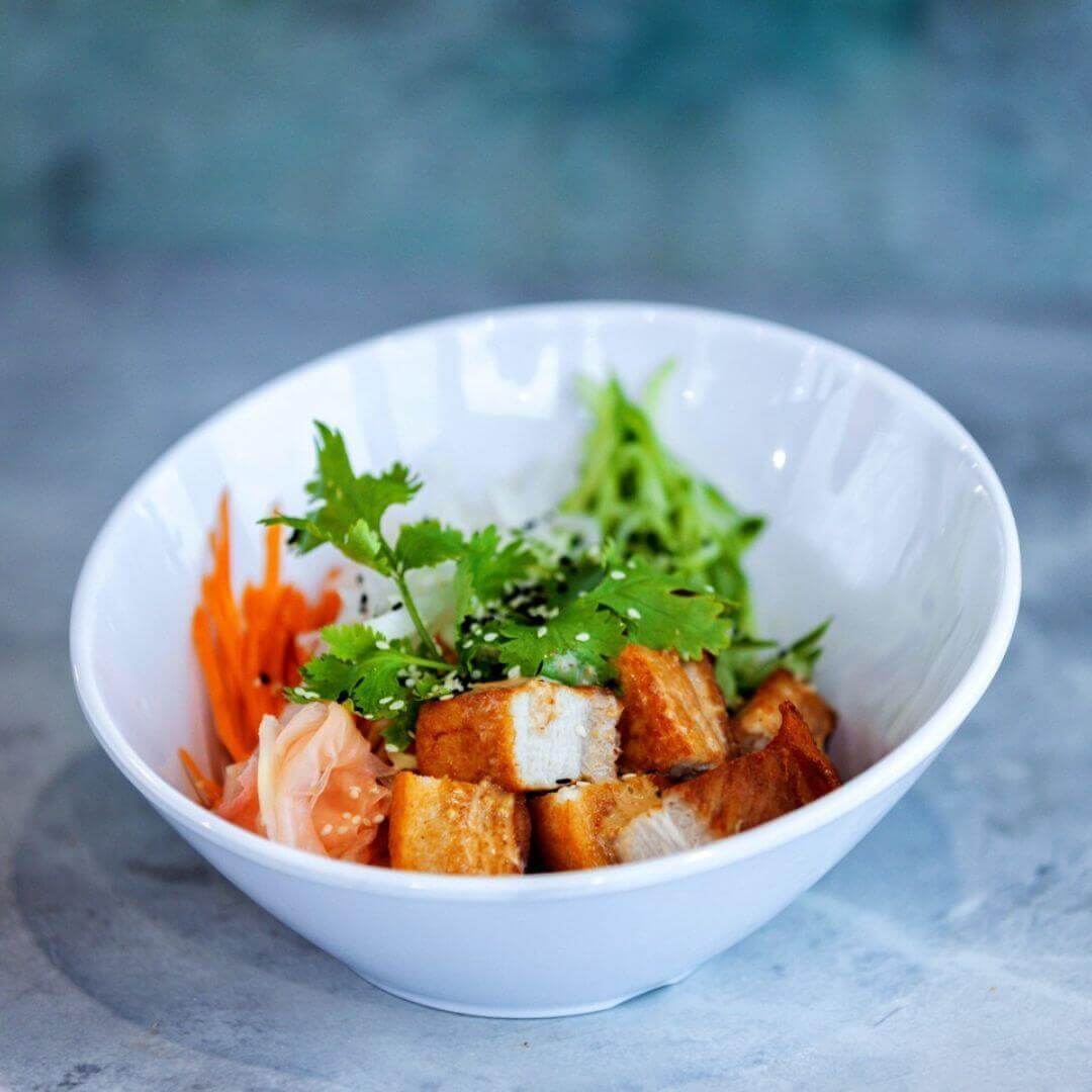 Fresh Asian-inspired poke bowl at Pier 62 featuring crispy tofu, pickled vegetables, cilantro, and sesame garnish