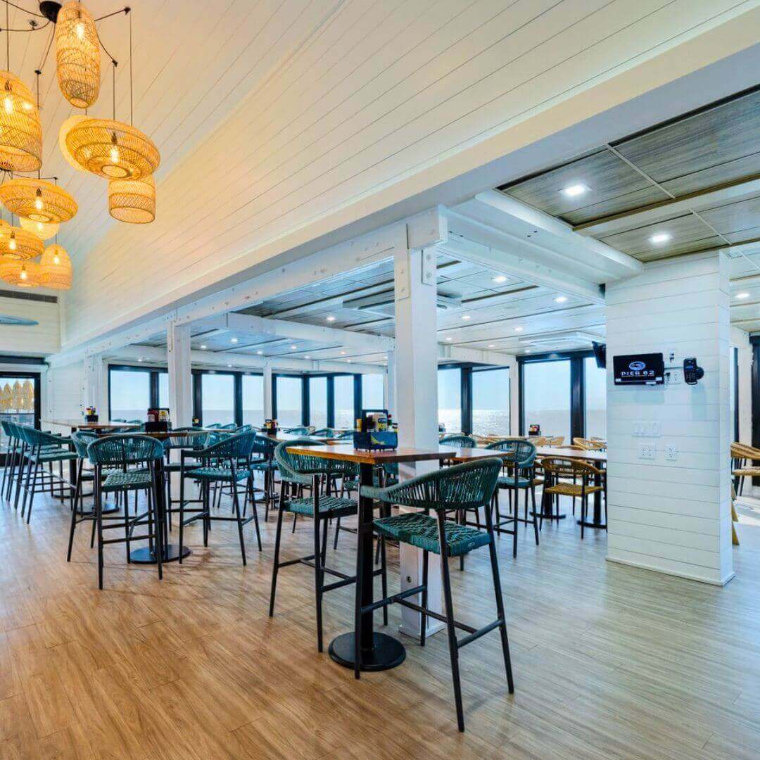 Modern bar area at Pier 62 Cocoa Beach featuring coastal-inspired wicker pendant lighting, turquoise bar stools, and panoramic ocean views