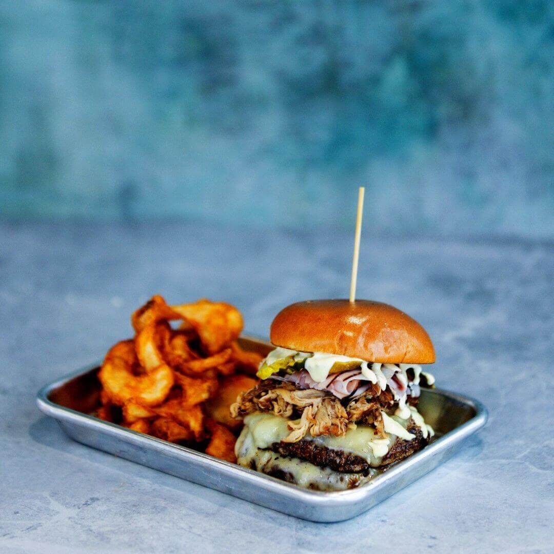 Signature pulled pork burger at Pier 62 Cocoa Beach topped with melted cheese and coleslaw, served with golden curly fries