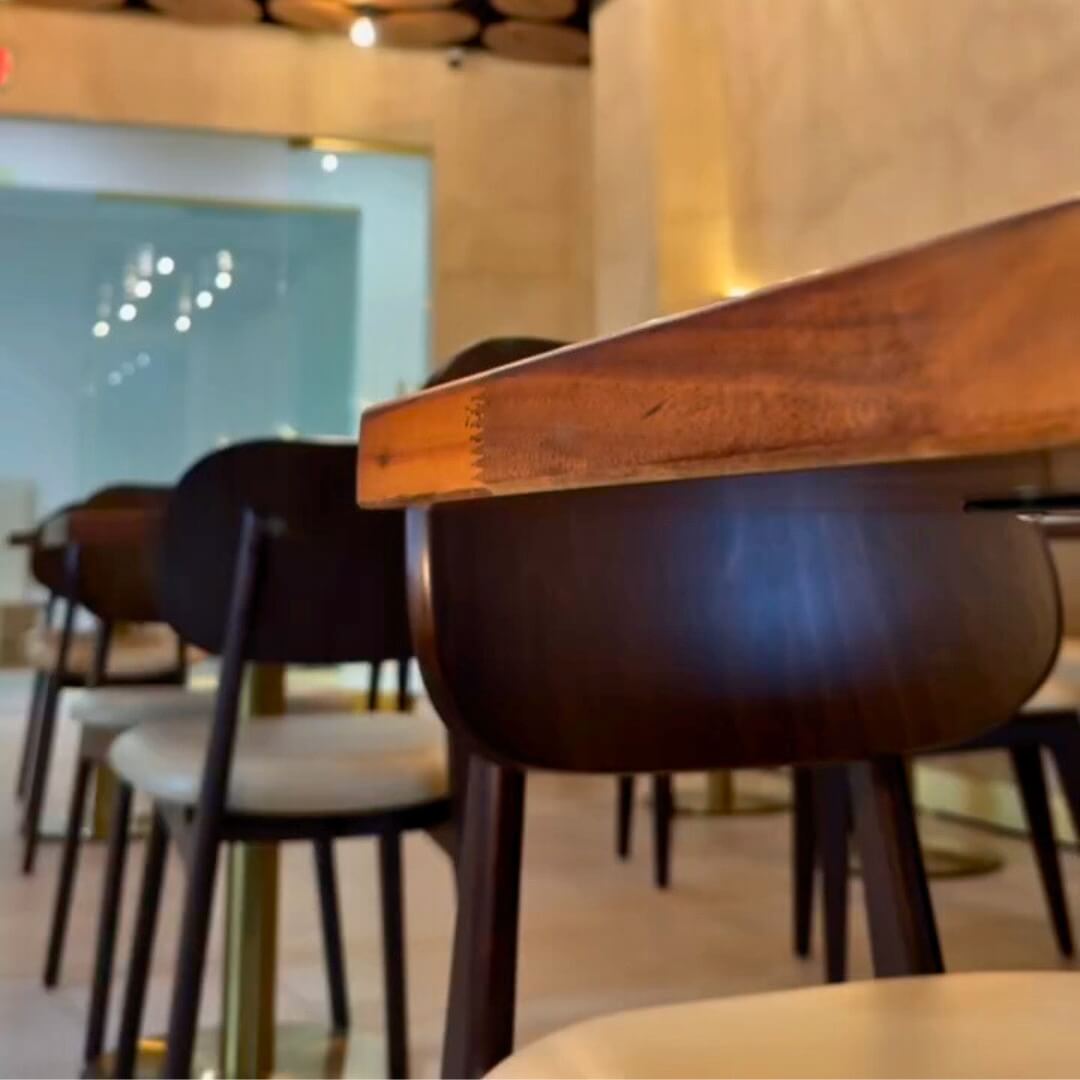 Interior of STL Cafe Miami featuring custom wood chairs, solid walnut tables, and decorative ceiling design